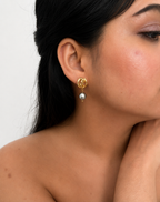 Woman wearing a gold Nordic knot drop earring with a 10 mm grey baroque freshwater pearl
