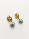Angled view of gold Nordic knot drop earrings with 10 mm grey baroque freshwater pearls