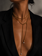 Close-up of a gold open beaded necklace with two 10 mm grey baroque freshwater pearl drops worn on the neck