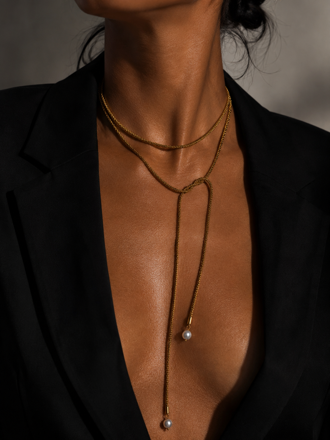 Close-up of a gold open beaded necklace with two 10 mm grey baroque freshwater pearl drops worn on the neck