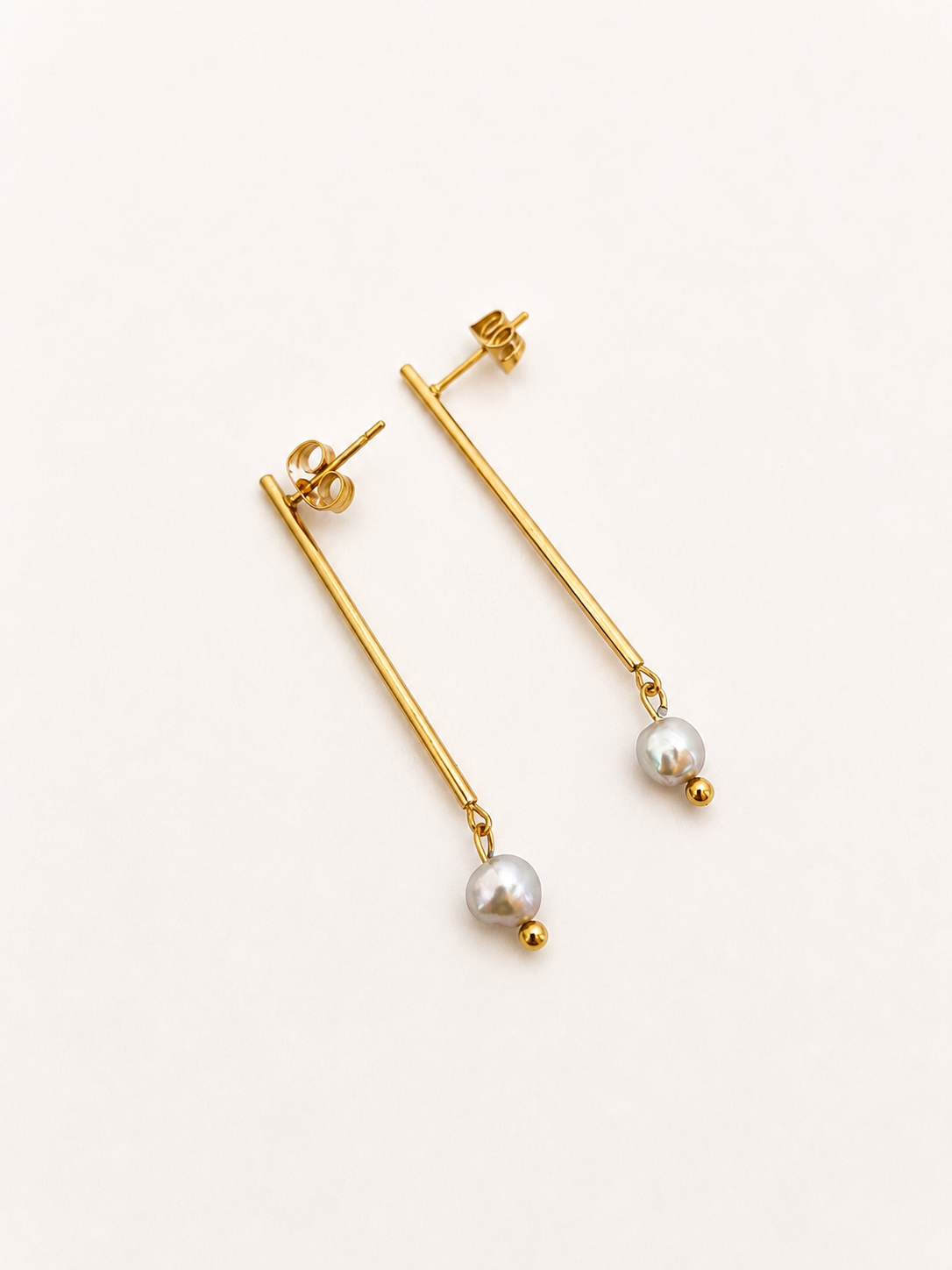 Back and angled view of gold linear drop earrings with 4 mm grey freshwater pearls and stud posts