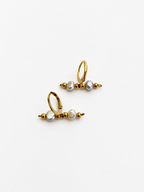 Front view of gold linear earrings with grey freshwater baroque pearls arranged between polished gold beads.