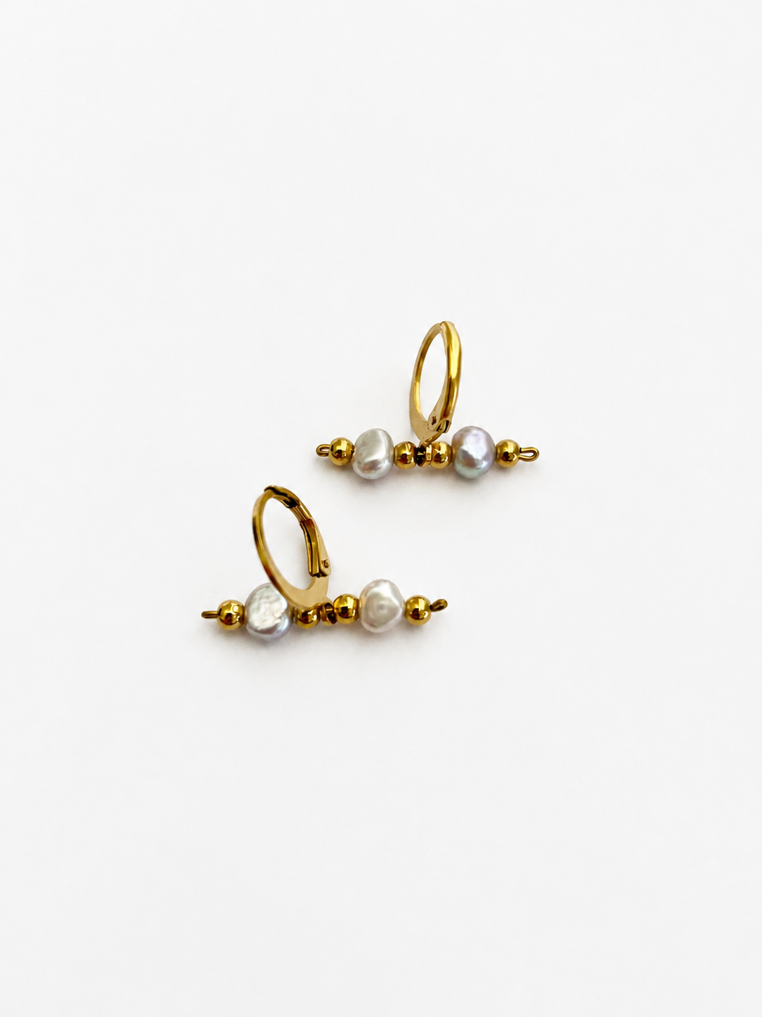 Front view of gold linear earrings with grey freshwater baroque pearls arranged between polished gold beads.