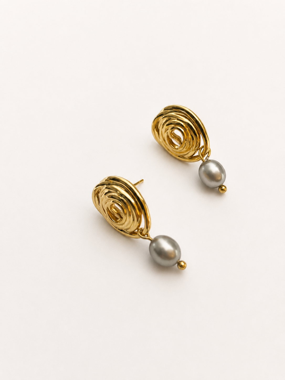 Pair of sculptural gold spiral stud earrings with 6 mm oval grey freshwater pearl drops.