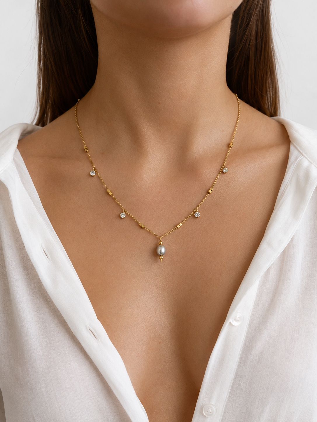 Woman wearing a gold necklace with an oval grey freshwater pearl and sparkling cubic zirconia accents