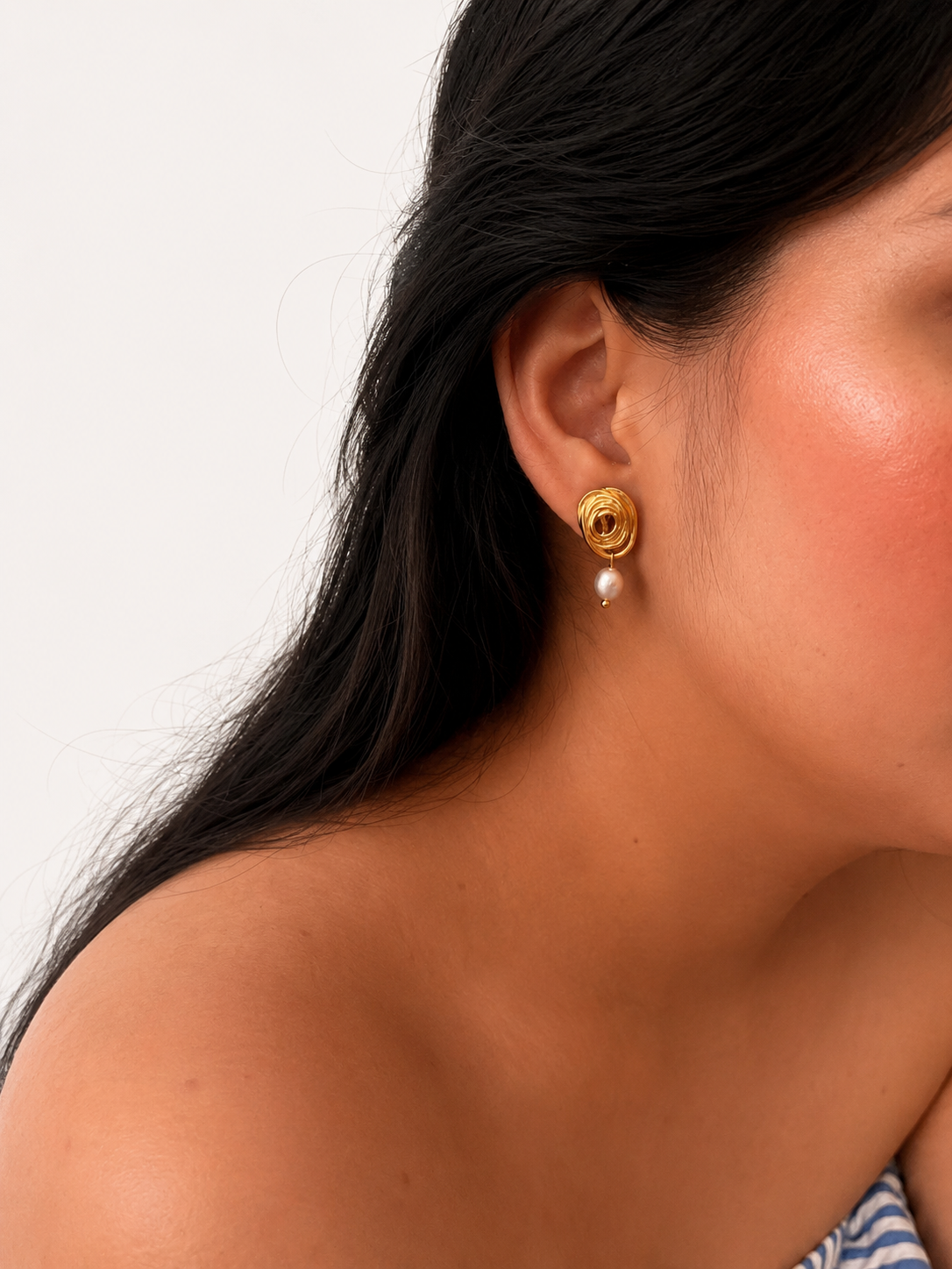 Woman wearing a sculptural gold spiral earring with a grey freshwater pearl drop