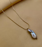 Organic grey baroque pearl necklace featuring a high-luster Keshi pearl suspended on a fine gold chain. Minimalist jewelry styling