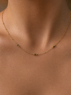 Close-up of a delicate gold necklace with 2 mm grey Keshi freshwater pearls and polished gold bead accents.