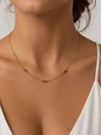 Woman wearing a delicate gold necklace with 2 mm grey Keshi freshwater pearls and gold bead accents.