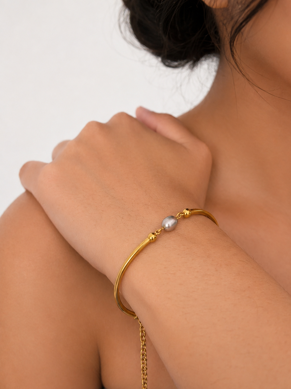Close-up lifestyle view of a gold bracelet with a 6 mm oval grey freshwater pearl and rounded gold sections