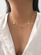 Woman wearing a gold Clover Bloom necklace with 6 mm grey freshwater pearls and clover-inspired details.