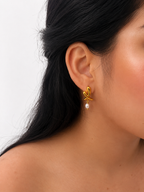 Close-up of a gold cross stud earring with a 6 mm oval grey freshwater pearl worn on the ear