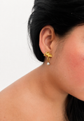 Close-up of a gold ginkgo leaf drop earring with a 6 mm oval grey freshwater pearl worn on the ear