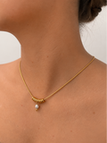 Close-up of a gold Ripple necklace with a 6 mm grey freshwater pearl and polished ring accents worn on the neck