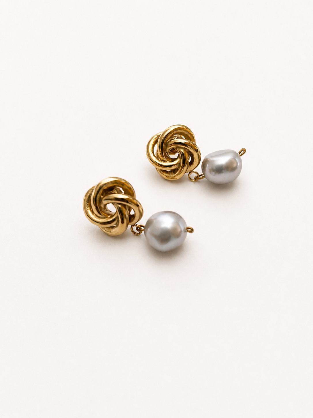 Angled view of gold Celtic knot earrings with organic grey baroque freshwater pearl drops