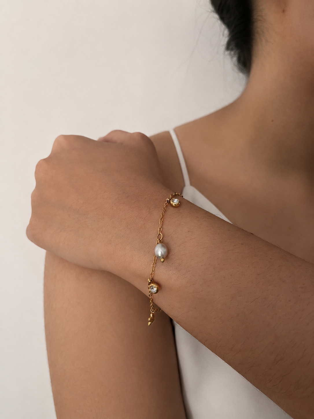 Gold chain bracelet with an oval grey pearl, clear stone charms and adjustable extender on the wrist