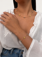 Lifestyle view of a gold Clover Bloom necklace with grey freshwater pearls and four-leaf clover accents.