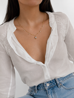 Lifestyle view of a gold necklace with a grey freshwater pearl pendant and cubic zirconia accents