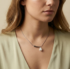 Close-up of a woman wearing a delicate necklace with a pearl pendant.