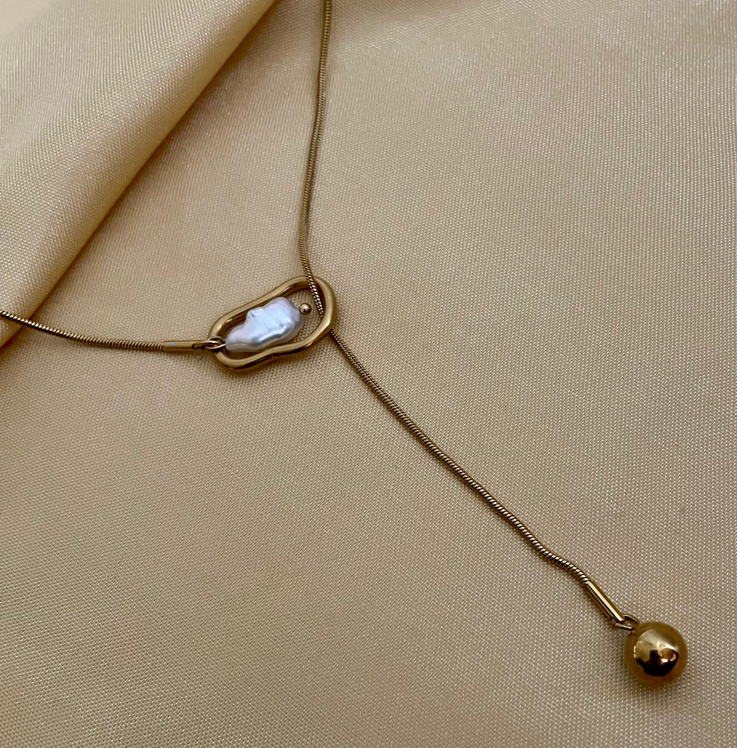 Gold necklace with a pendant on a beige fabric background