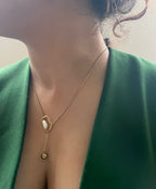 Gold necklace with a pendant worn by a person in a green outfit.