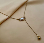 Gold necklace with a pendant on a beige fabric background