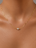 Close-up of a gold Waves necklace with a 6 mm oval light grey freshwater pearl worn on the neck