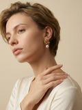 Parisian chic editorial portrait featuring elegant gold knot pearl earrings styled with a deep-neck ivory silk shirt