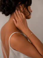 Side view of a woman wearing a minimalist gold sun charm bracelet with small white freshwater pearls