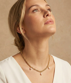 Model wearing a dainty gold wheat chain necklace with pearl pendants, styled with a white silk top for a minimalist bridal or evening look