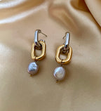 Close-up detail of mixed metal chain link earrings with grey pearl drops worn on the ear.