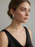 Woman wearing Naomi modern gold drop earrings with round black pearls. Elegant architectural jewelry styled for evening or professional wea