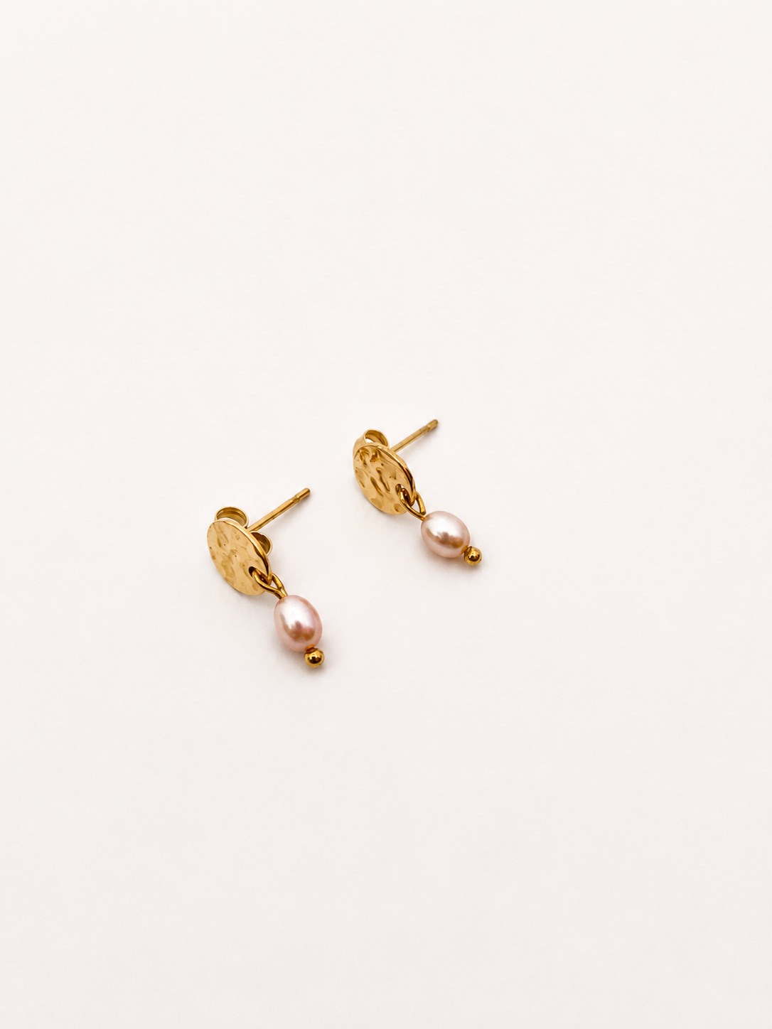Pair of gold stud earrings with 5 mm natural pink oval freshwater pearl drops.