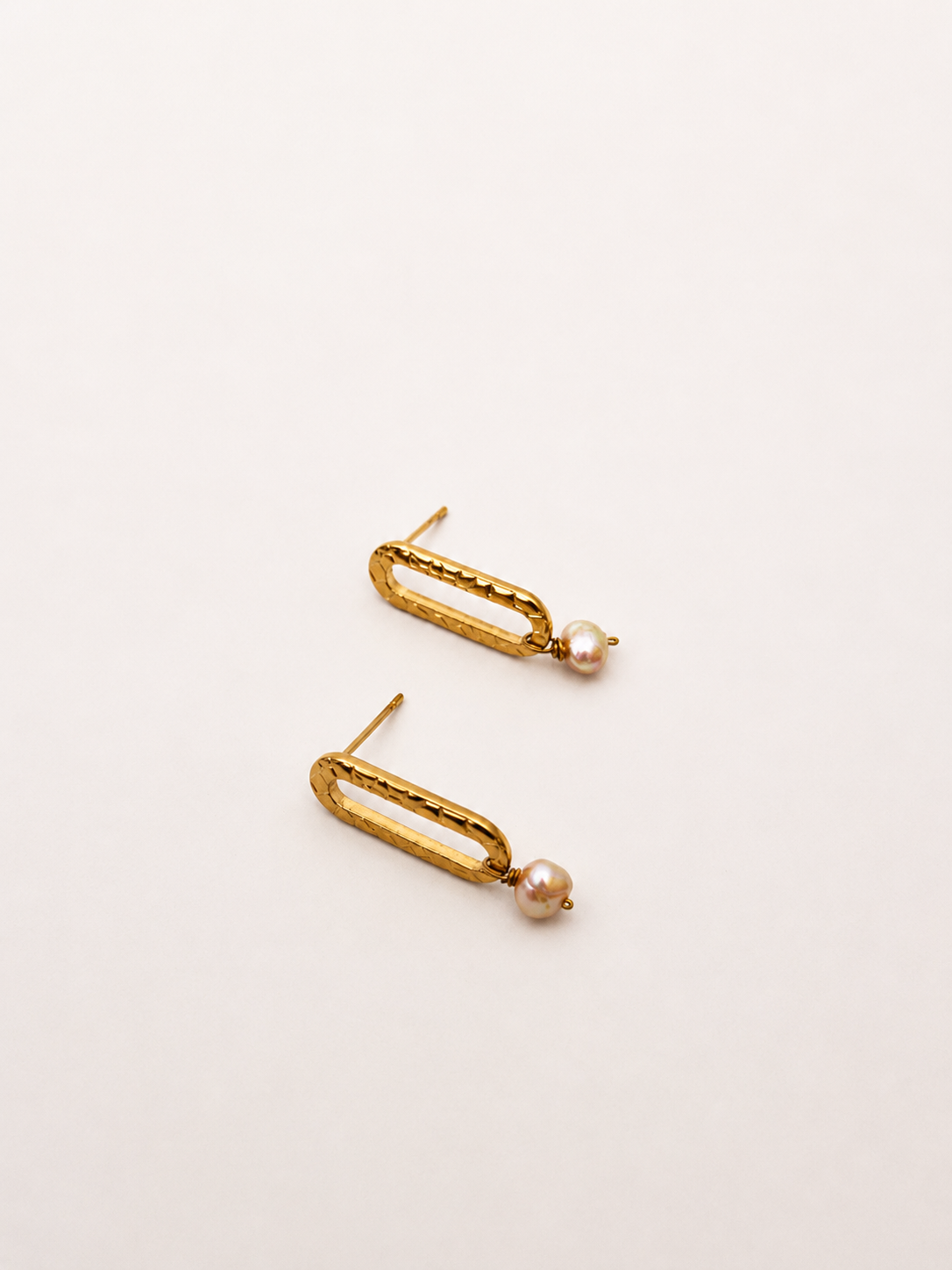 Pair of minimalist gold stud earrings with 5 mm natural pink oval freshwater pearl drops.