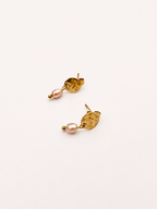 Angled view of gold stud earrings with 5 mm natural pink oval freshwater pearls.