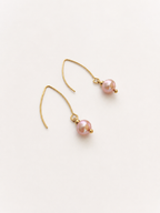 Angled view of gold drop earrings with 8 mm natural pink round freshwater pearls