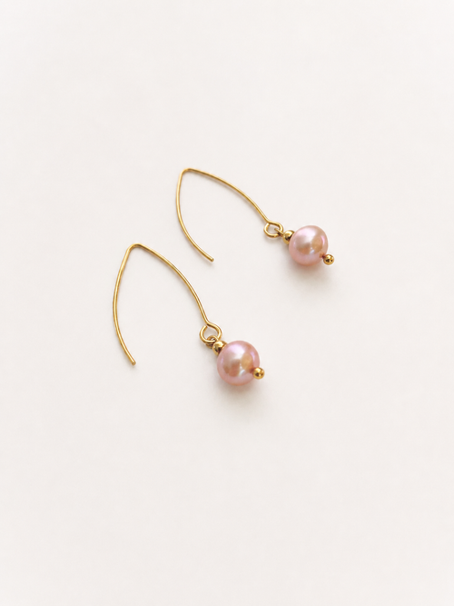 Angled view of gold drop earrings with 8 mm natural pink round freshwater pearls