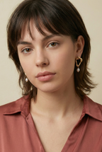 woman wearing sculptural gold earrings with a delicate freshwater pearl drop, ideal for weddings, office and casual night outs