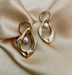 18k gold plated organic shape drop earrings featuring a lustrous white freshwater pearl, worn in a luxury editorial setting