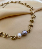 Gold chain bracelet with pearls on a beige fabric background
