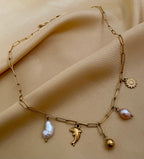 Elegant gold charm necklace with organic baroque pearls and sea-inspired pendants Parisian chic jewelry style
