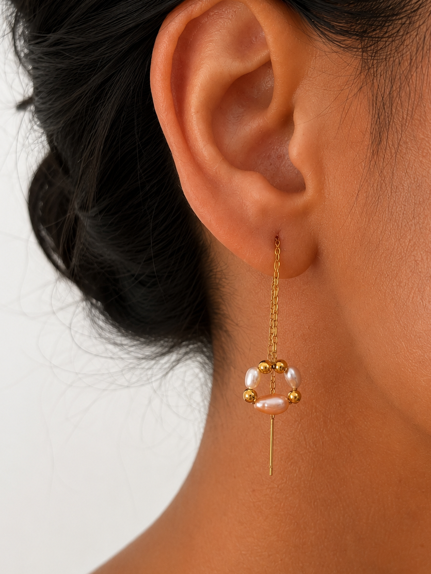 Close-up of a gold threader earring with oval white and blush freshwater pearls arranged in a circular bouquet