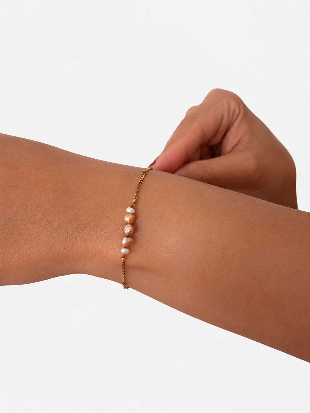 Dainty gold chain bracelet with mixed pink, white and golden baroque freshwater pearls on the wrist