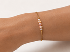Close-up of a gold chain bracelet with petite white, pink and golden baroque pearls and a pink centre pearl