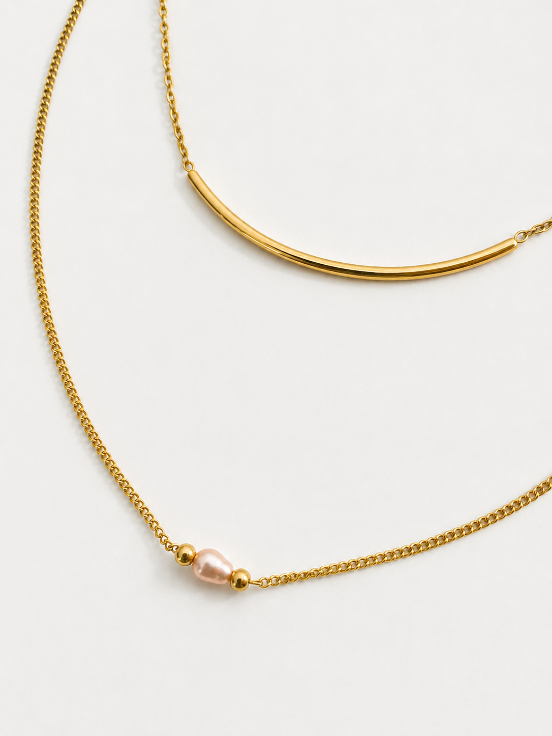 Gold layered Arc necklace with a curved bar and 4 mm oval pink freshwater pearl framed by gold beads