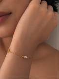 Woman wearing a delicate gold bracelet with a blush-pink pearl and polished gold beads