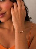 Woman wearing a delicate gold chain bracelet with pink, white and golden freshwater pearls