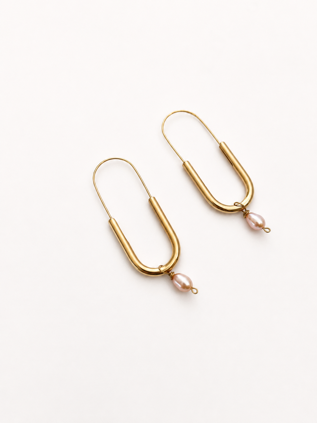 Angled view of gold paperlink earrings with oval pink freshwater pearl drops