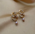 Gold chain earrings with pearl drops on a beige fabric background