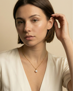 Minimalist fine jewelry styling showing a single freshwater pearl drop necklace on a delicate gold beaded chain, highlighting the high-luster nacre and skin texture